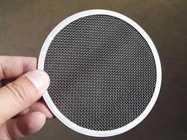 A filter disc made of black wire cloth with stainless steel edge.