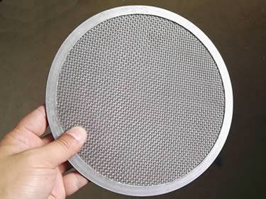 There is a stainless steel filter disc in a hand.