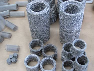 Many stainless steel ring type compressed knitted mesh filters on the ground.